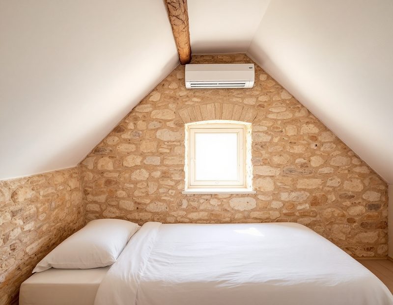 Climatisation murale dans une chambre sous les toits, mur en pierre